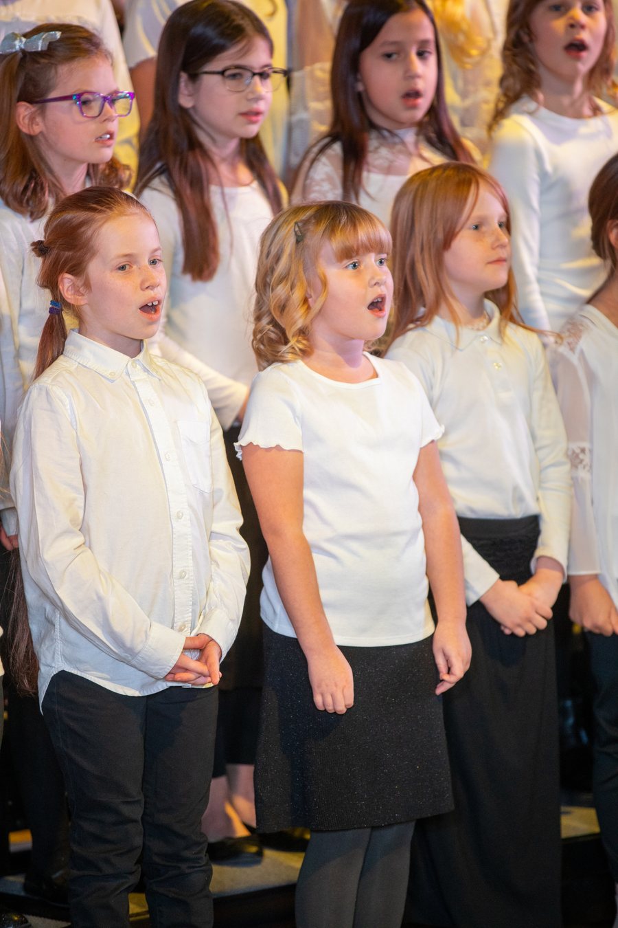 Young choir members singing in white concert dress